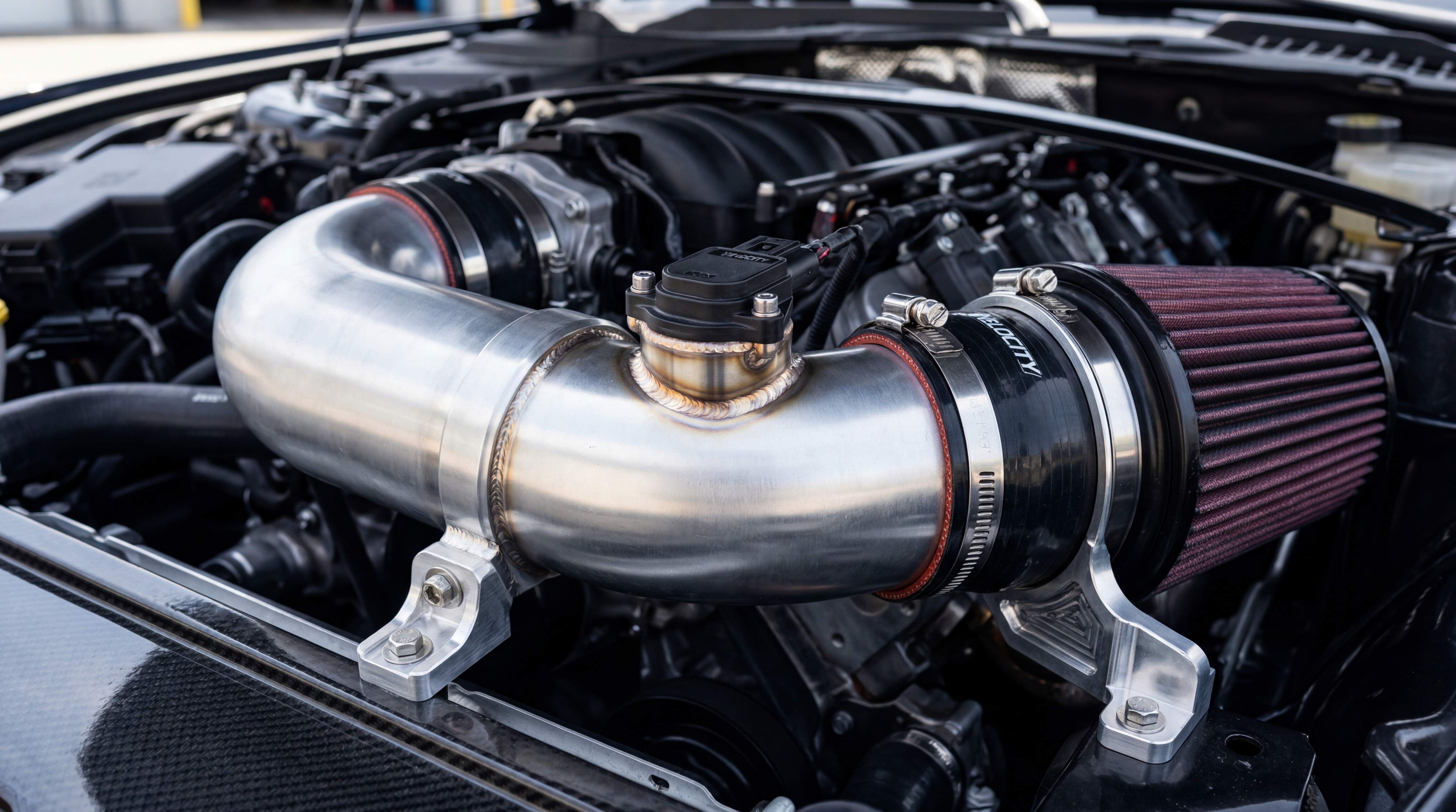 Aftermarket intake pipe with sensor housing, silicone coupler, clamp and cone filter showing precise sensor fitment and connection quality